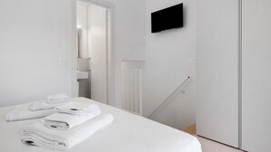 Een hotelkamer met een bed, een aan de muur bevestigde televisie en een deur naar een badkamer.