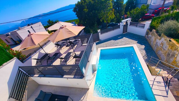 Ein Pool auf dem Dach mit Meerblick, Sitzgelegenheiten im Freien und ein modernes architektonisches Design.
