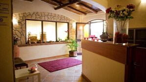 A cozy interior with a stone wall, a wooden ceiling, a dining area with a table and chairs, and a kitchen area with a counter and a vase of flowers. - Mediterraneo B&B (Pizzo)