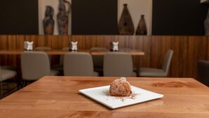 A dessert on a square plate on a wooden table in a restaurant with a dark wall and decorative vases. - Mediterraneo B&B (Pizzo)