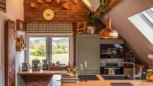 Cucina con isola in legno, macchina da caffè, bollitore e vista sull'esterno.