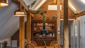 Un'area pranzo con tavolo e sedie in legno, un lampadario e una parete in mattoni con scaffali.