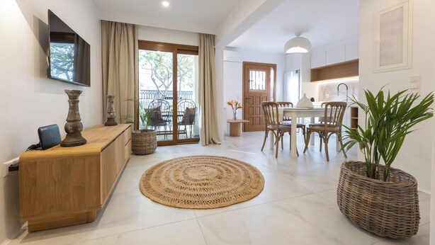 Una sala de estar moderna con comedor, televisor montado en la pared y balcón con vistas.