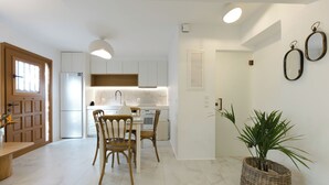 Una cocina moderna con armarios blancos, una mesa de comedor con sillas y una planta en maceta.