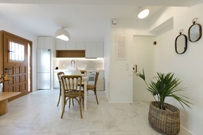 Una cocina moderna con armarios blancos, una mesa de comedor con sillas y una planta en maceta.