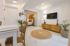 A modern bedroom with a bed, bedside table, TV, and a large mirror. - White Embrace | Two Bedroom Apartments (Naxos)