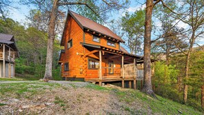 A log cabin with a porch, surrounded by trees. - Covered Deck + Fire Pit + Mountain Views | Near Smokies | Isaiah's Cabin (Townsend)