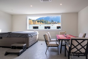 Ein Zimmer mit Billardtisch, Esstisch mit Stühlen, Fenster mit Bergblick und einer kleinen Stehleiter.