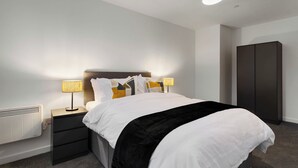 A modern hotel room with a neatly made bed, bedside lamps, a wardrobe, and a radiator. - City Point Aberdeeen by Guestz (Aberdeen)