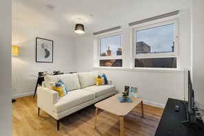 A modern living room with a sofa, a coffee table, a TV, and a dining area. - City Point Aberdeeen by Guestz (Aberdeen)
