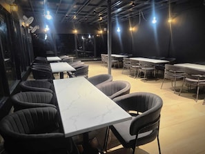 Un restaurante con mesas y sillas, ventiladores de techo e iluminación colgante.