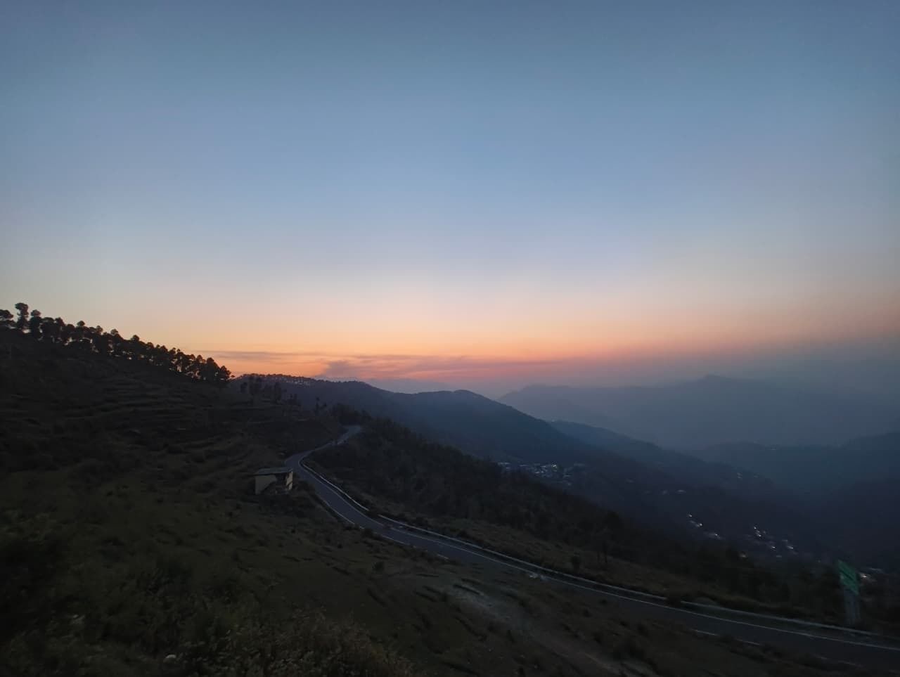 A winding road through a hilly landscape with a clear sky.