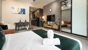 A hotel room with a bed, a desk, a chair, a TV, and a sliding door leading to a living area. - Sunsuria Forum Premier Suites Setia Alam (Shah Alam)