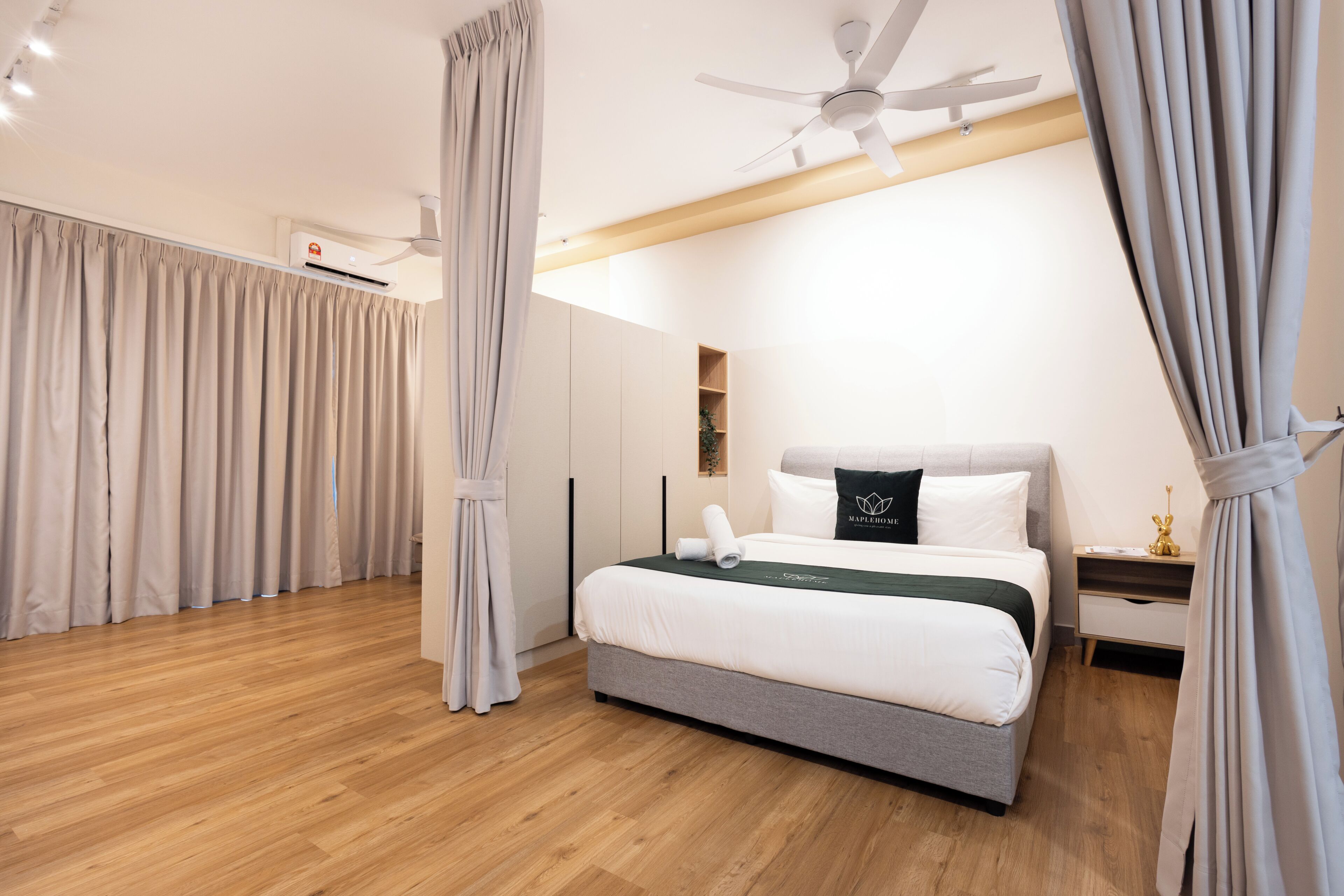 Una habitación de hotel moderna con cama, cortinas, ventilador de techo y aire acondicionado de pared.