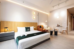 Una habitación de hotel moderna con una cama grande, mesitas de noche, un escritorio y una zona de estar.