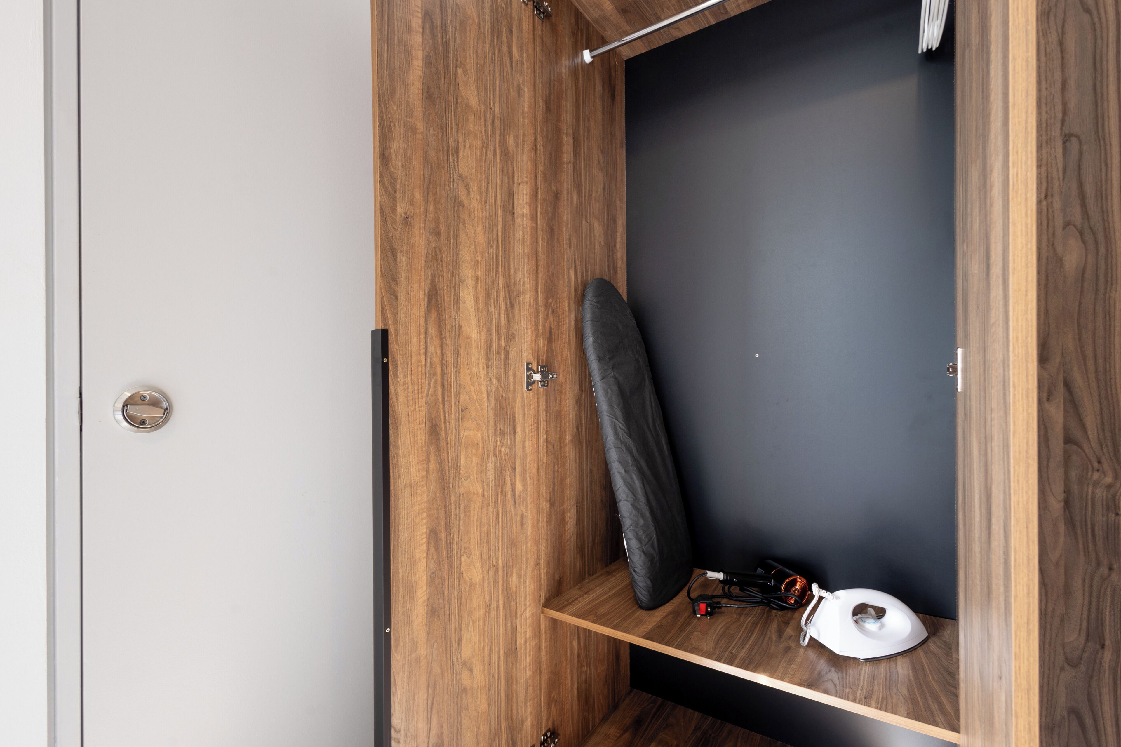 A wardrobe with a dark interior, a hanging garment, and a white object on the shelf.