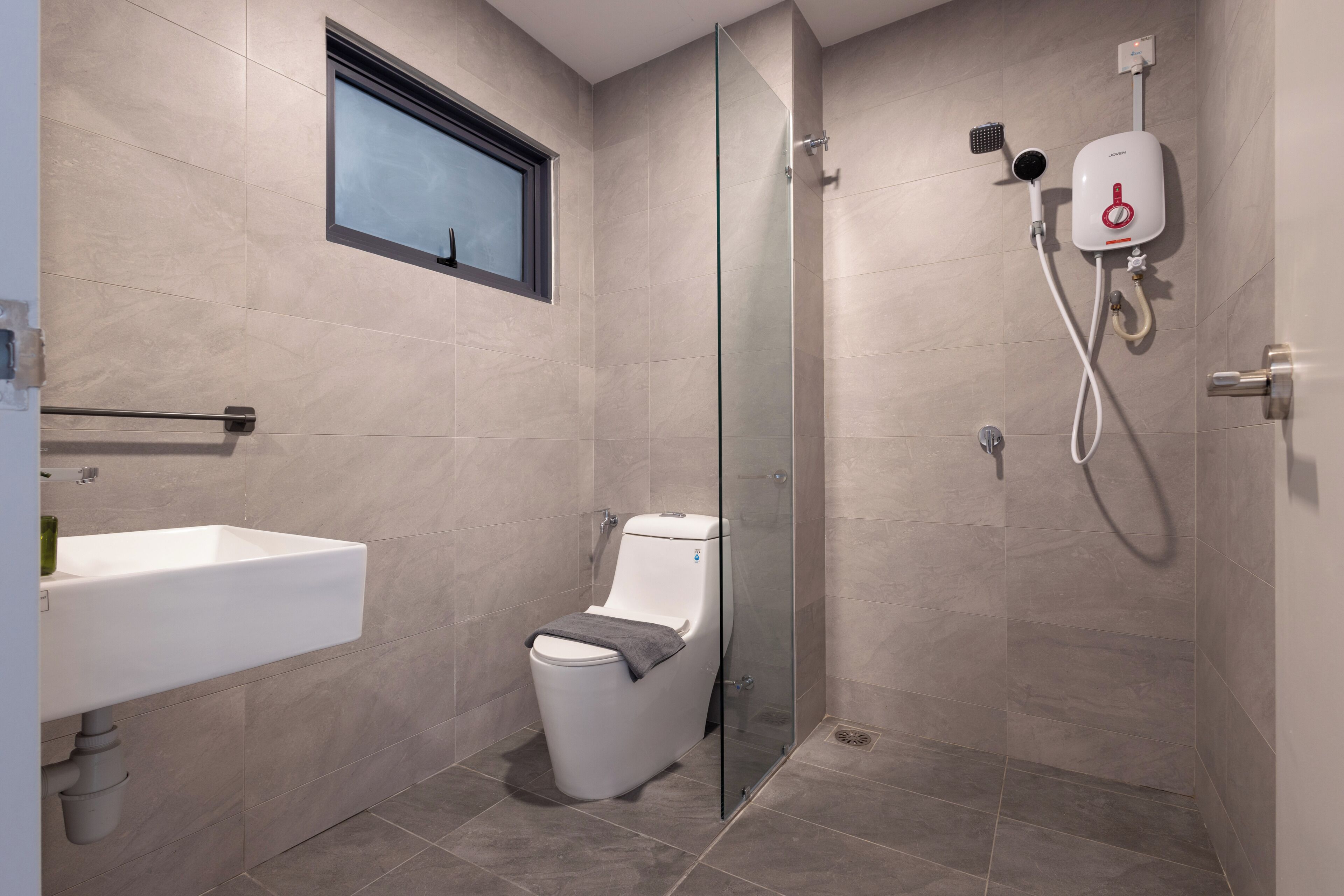 A modern bathroom with a glass shower enclosure, a toilet, and a sink.