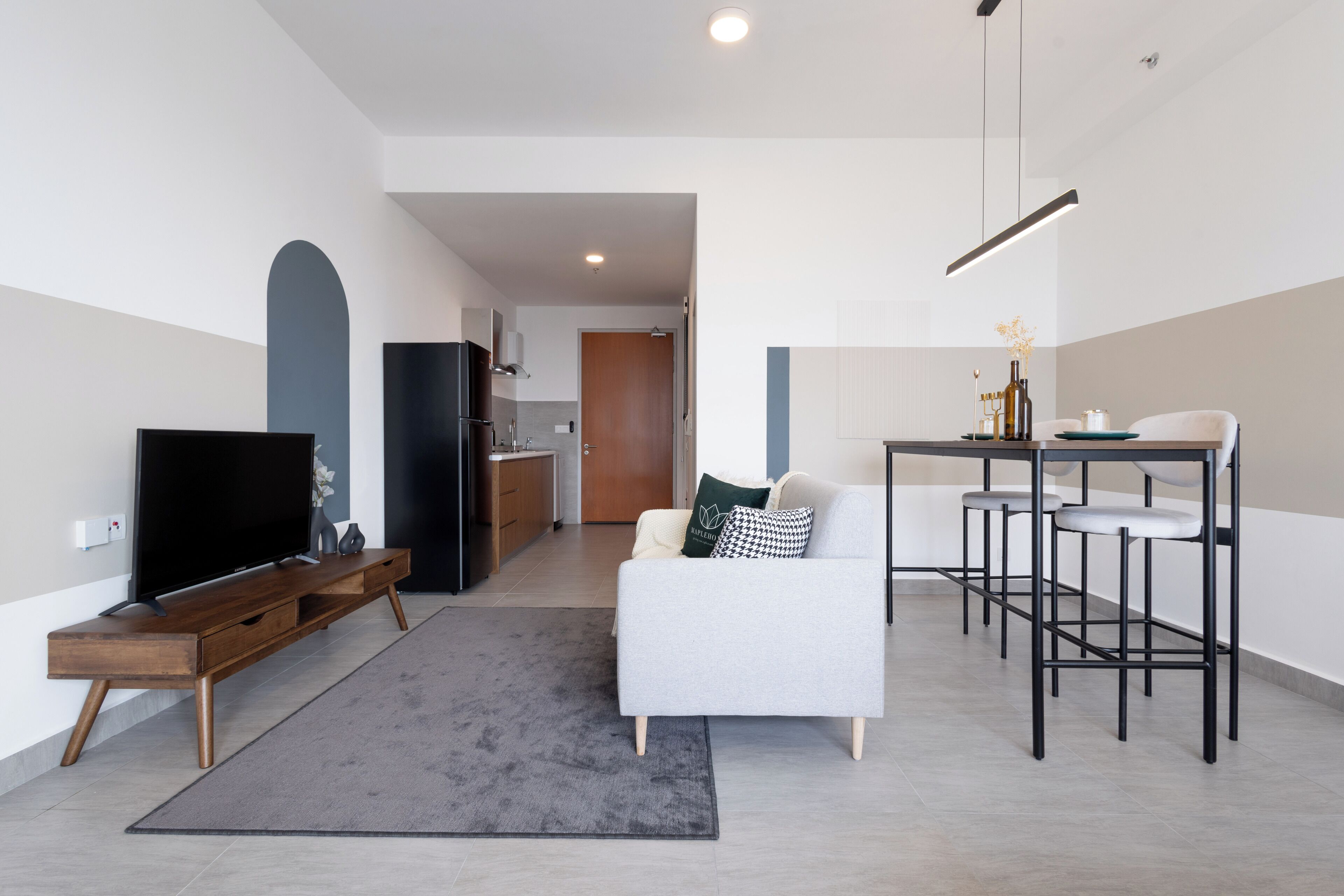 A modern living room with a flat-screen TV, a sofa, a coffee table, and a dining area with a table and chairs.