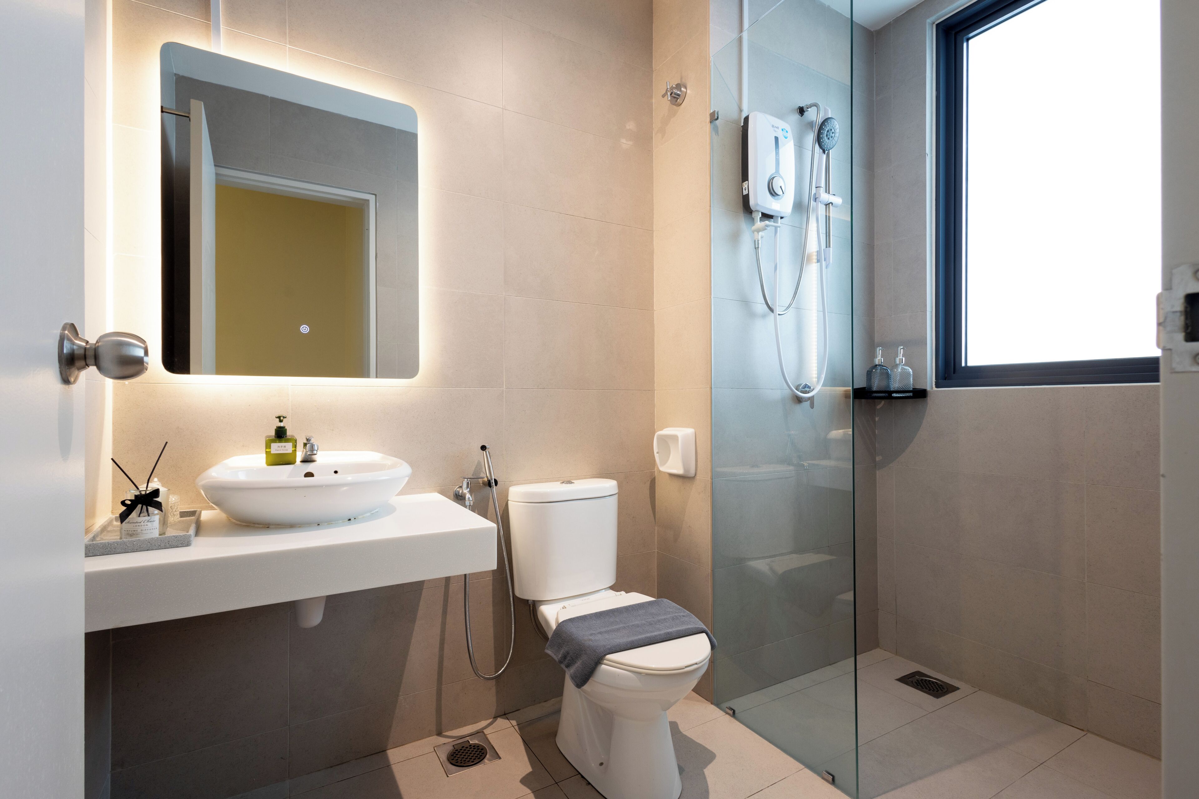 A modern bathroom with a glass-enclosed shower, a white sink, and a toilet.
