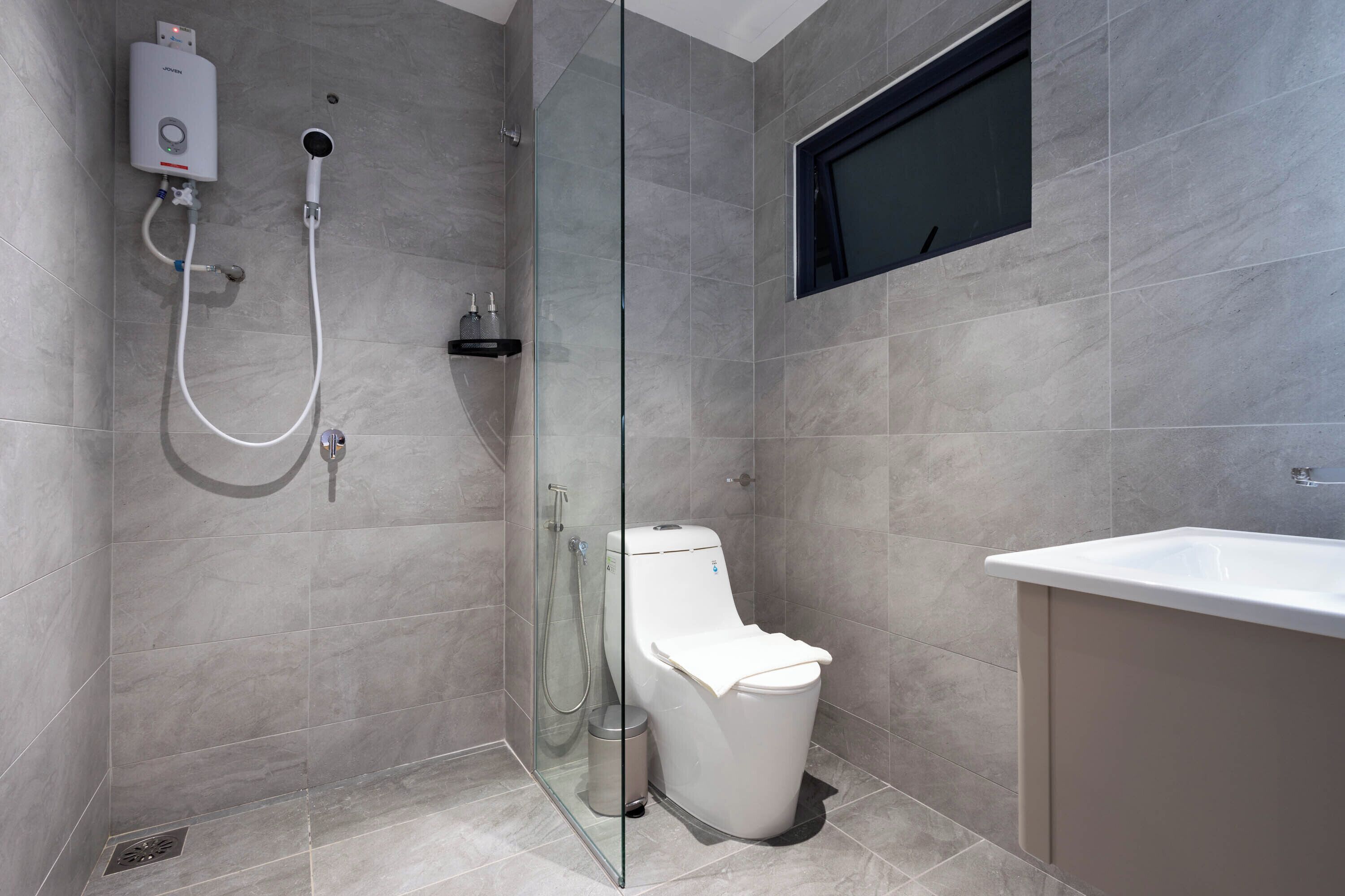A modern bathroom with a glass-enclosed shower, a white toilet, and a sink.