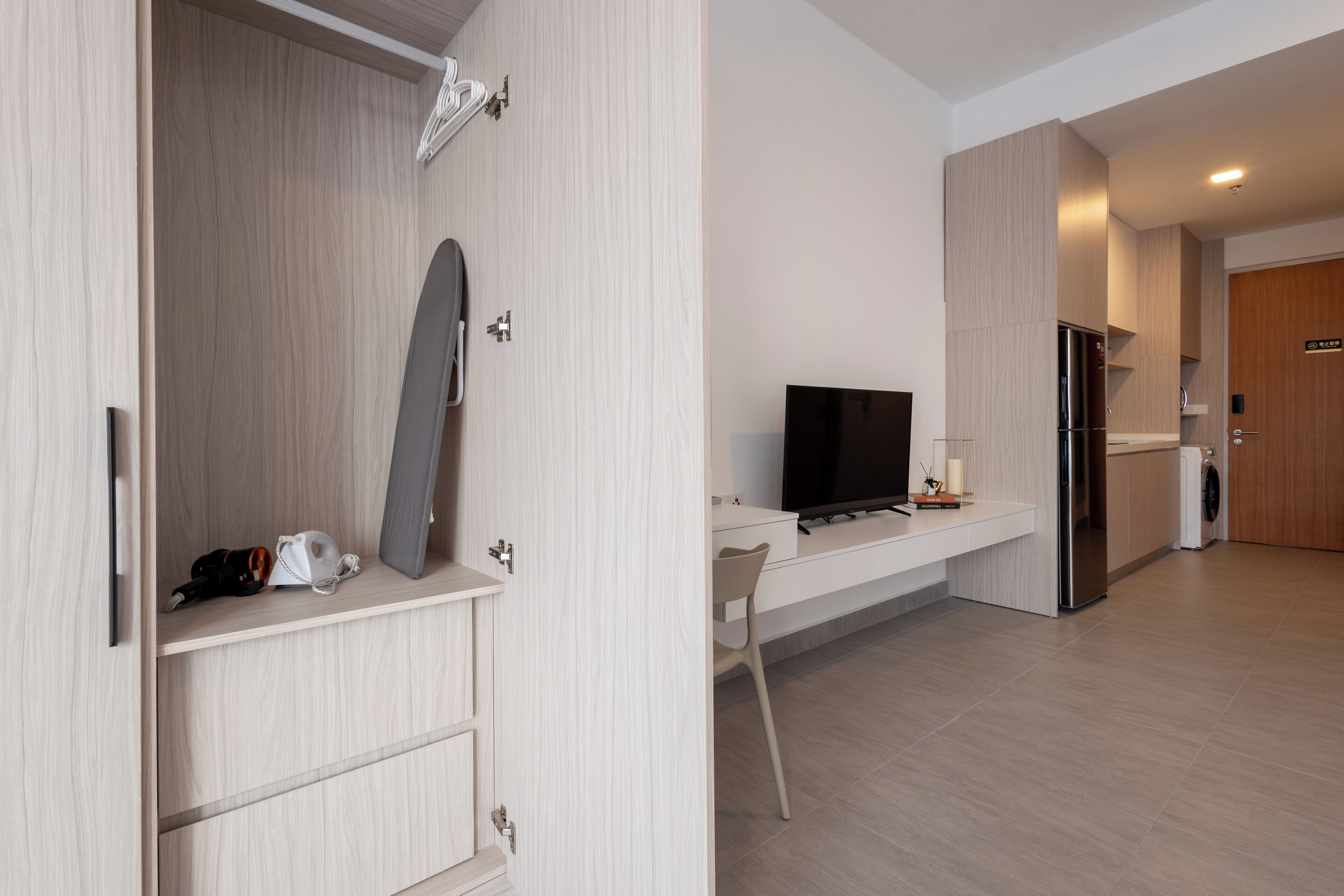 A modern kitchen with a built-in refrigerator, a flat-screen TV, and a white countertop.