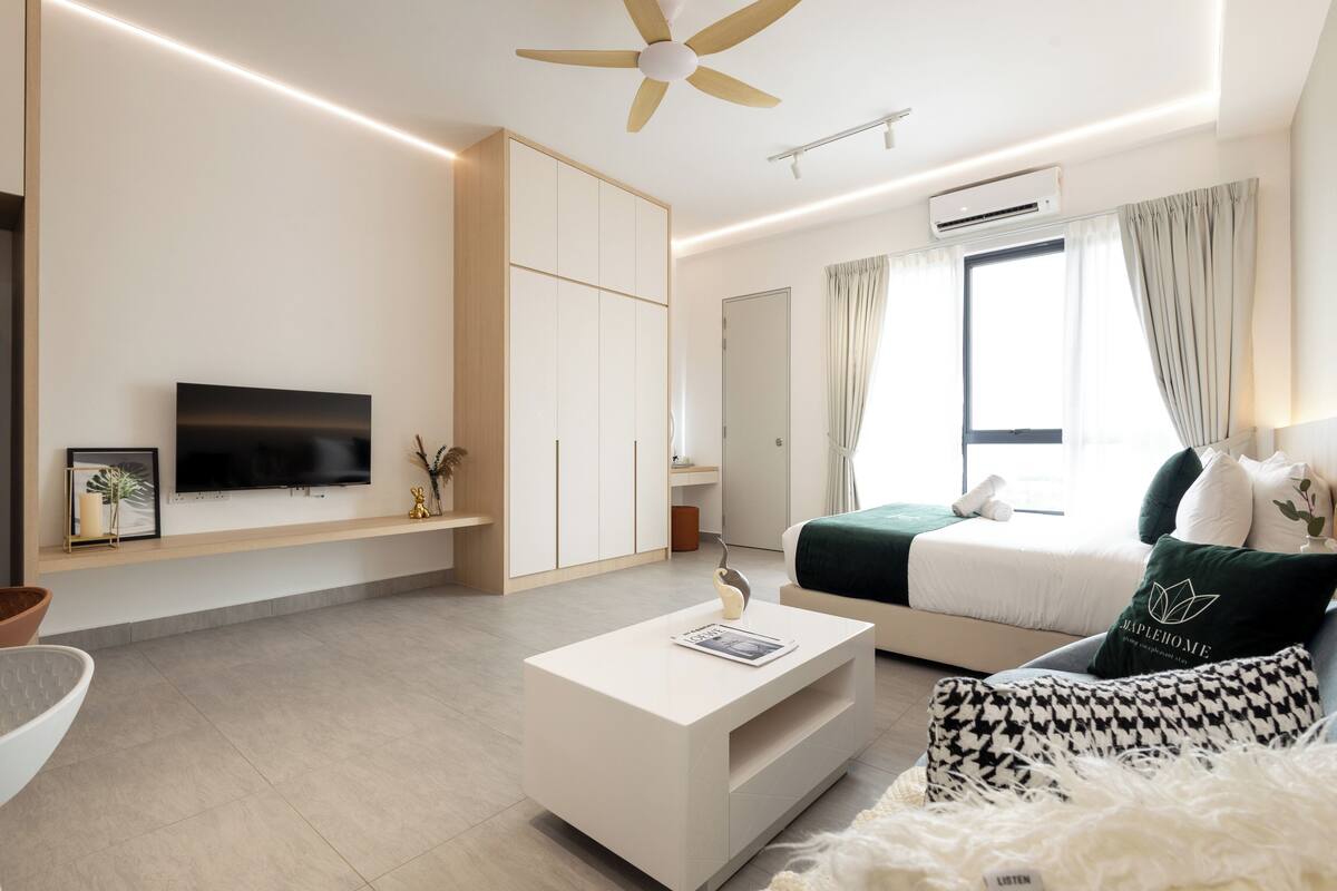Un dormitorio moderno con una cama, un televisor, un ventilador de techo y una ventana con cortinas.