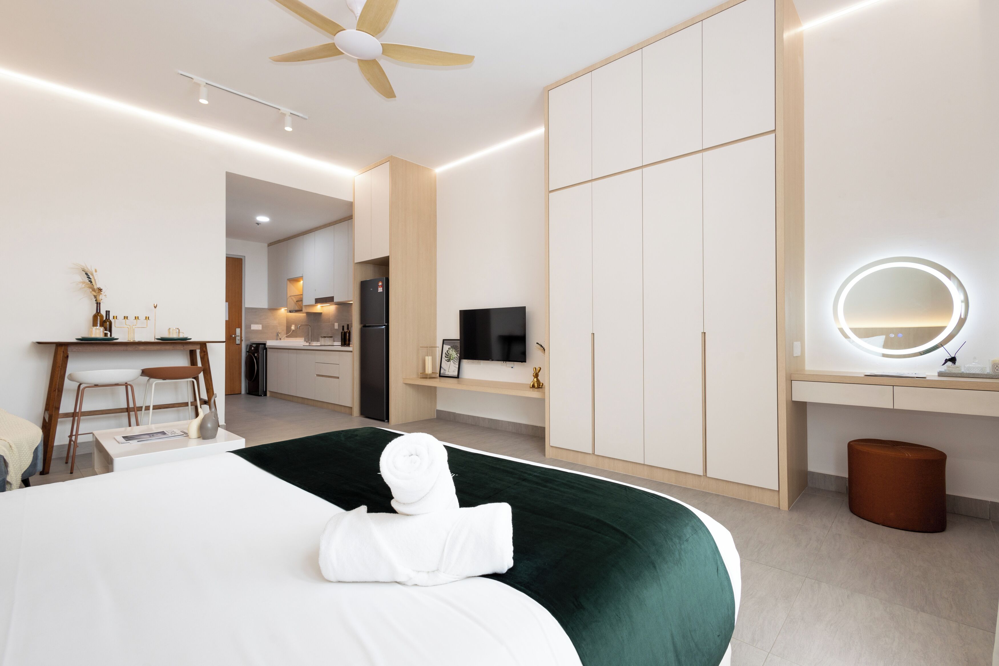 A modern hotel room with a bed, a desk, a television, and a bathroom mirror.