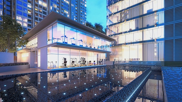 Un edificio moderno con fachada de vidrio, equipo de ejercicio al aire libre y una piscina reflectante.