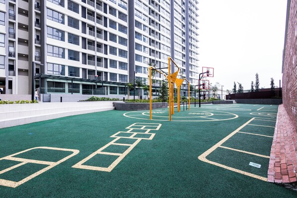 A multi-story building with a rooftop playground featuring a basketball hoop and exercise equipment.
