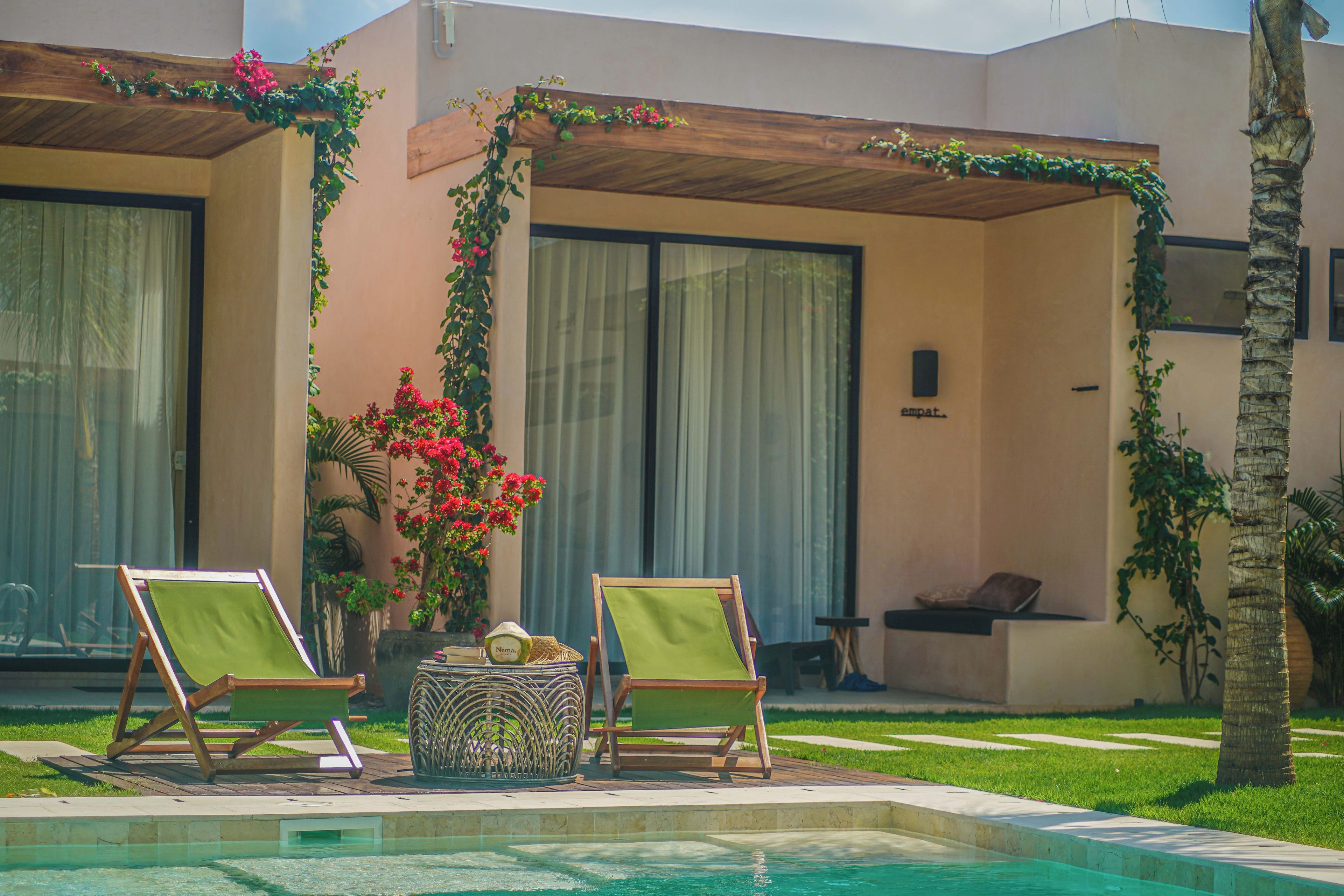 Un espace aménagé au bord de la piscine, comprenant deux chaises longues, une petite table et une plante décorative.