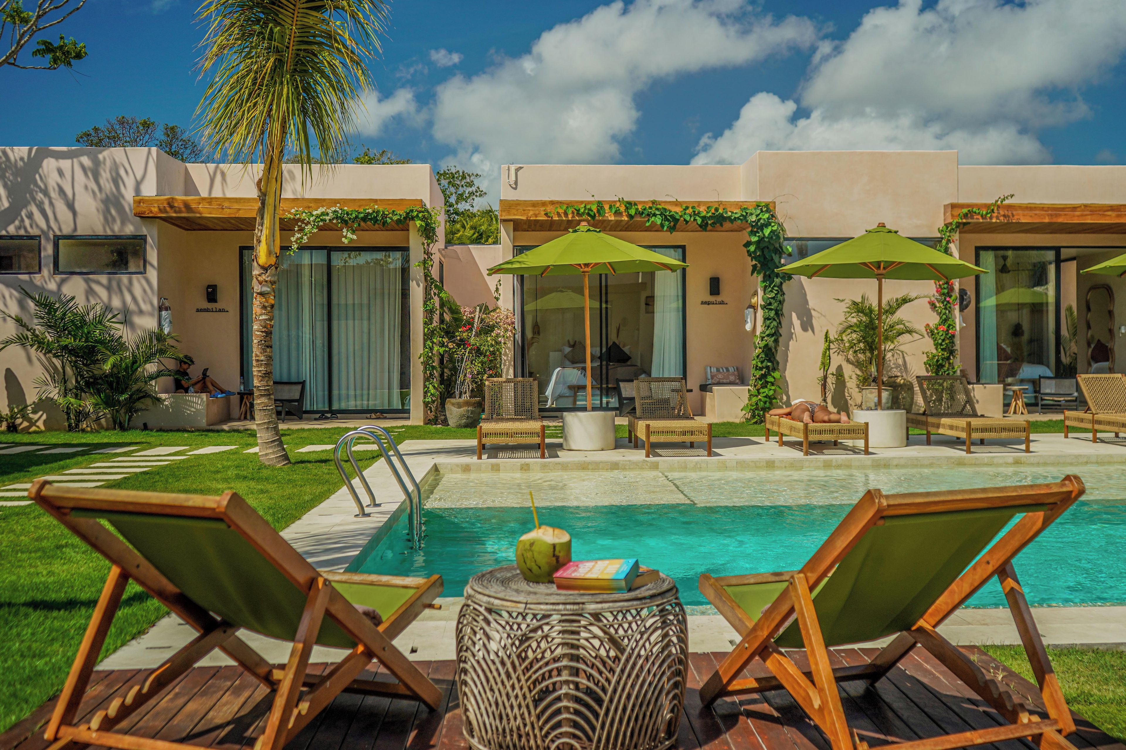 A poolside area with lounge chairs, a small table with a drink, and a clear view of the pool.
