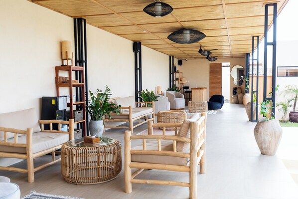 A modern lounge area with wooden furniture, large windows, and indoor plants.
