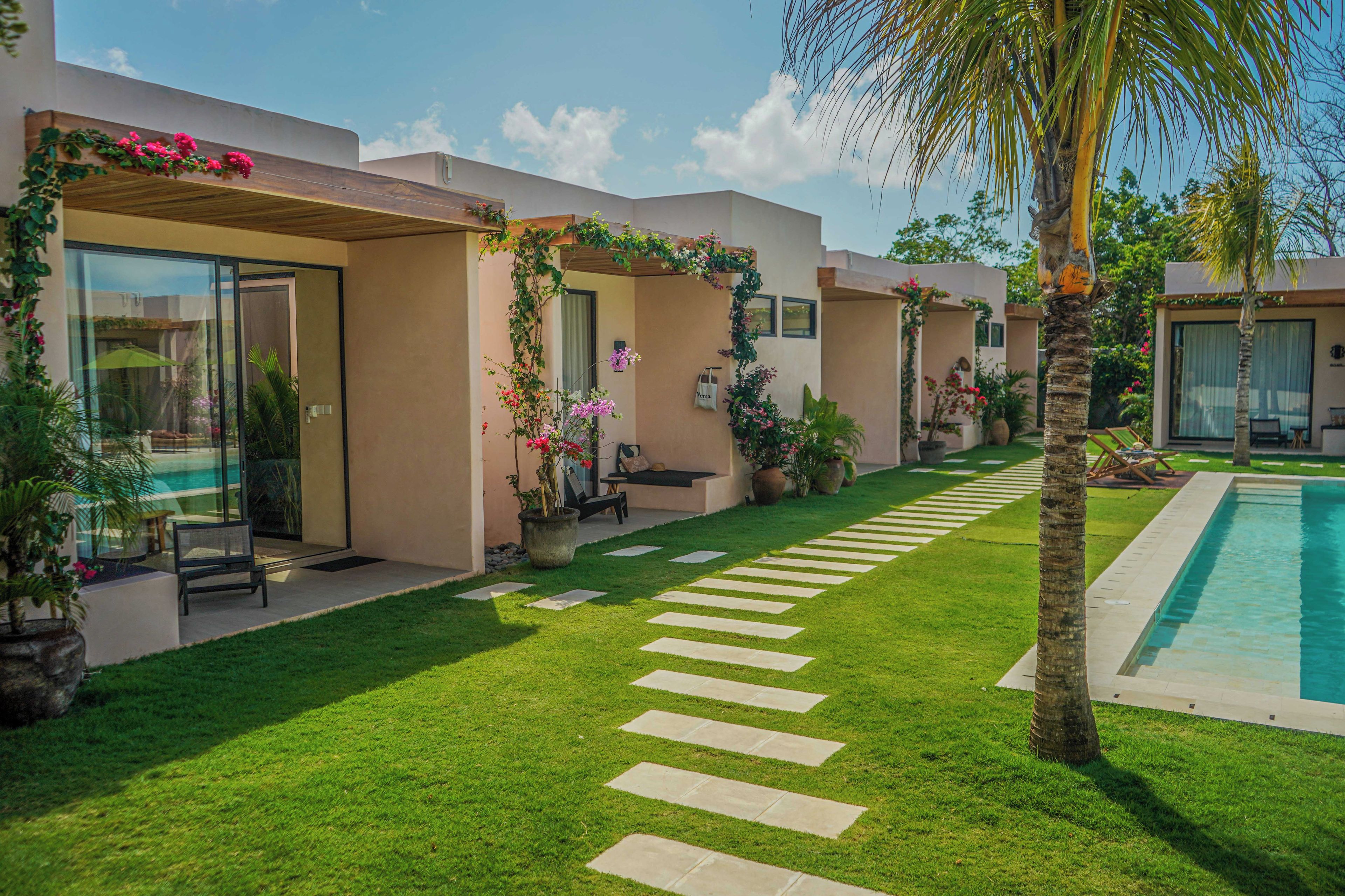 A modern resort with a swimming pool, a well-maintained lawn, and a pathway leading to the pool.