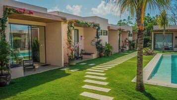 A modern resort with a swimming pool, a well-maintained lawn, and a pathway leading to the pool.