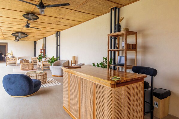 A modern living room with a wooden reception desk, a blue chair, and a bookshelf.