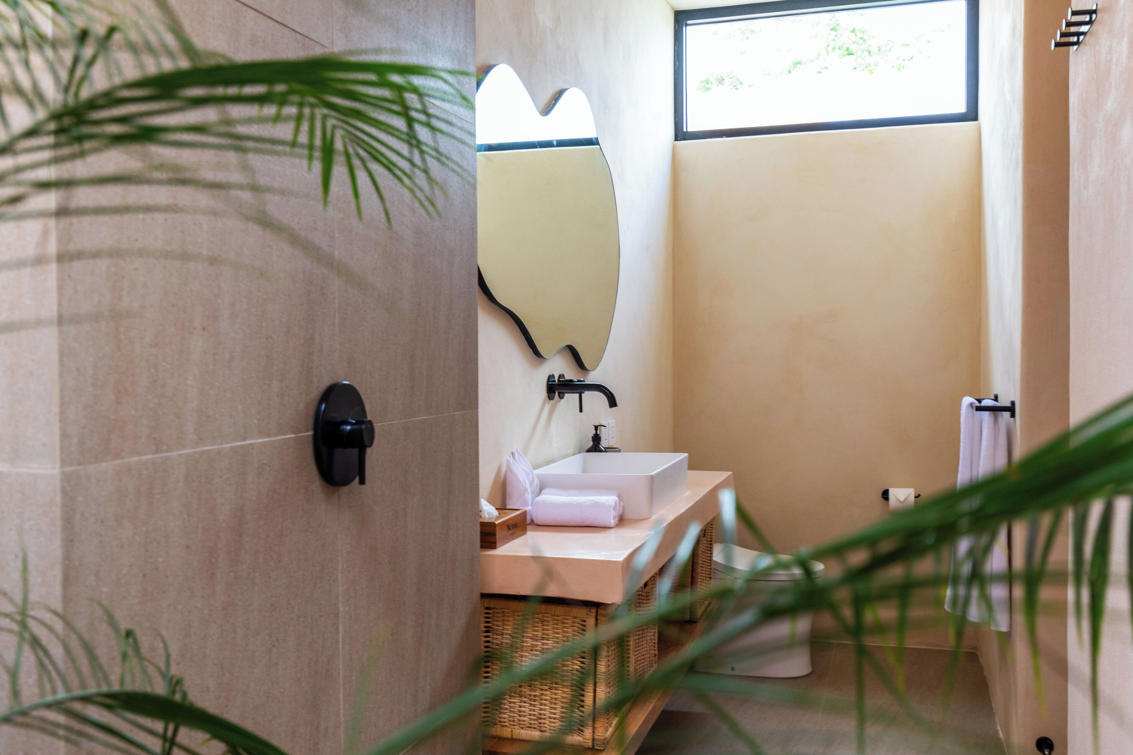Un baño con lavamanos, espejo y ventana.
