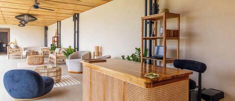 A modern living room with a wooden reception desk, a blue armchair, and a bookshelf.
