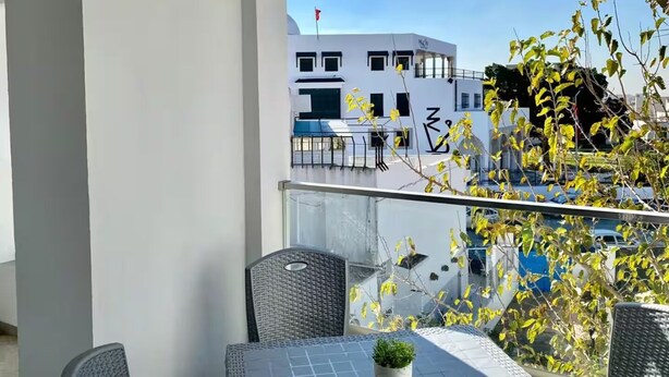 A balcony with a table, chairs, and a potted plant. - sandra 11 (La Marsa)