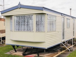 A mobile home with three windows, a door, and a small porch area.
