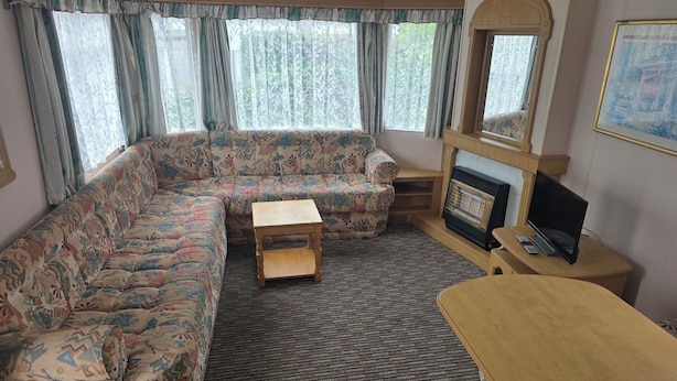 A living room with a sofa, a small wooden table, a fireplace, and a television.