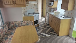 A compact RV kitchen with a stove, microwave, and wooden cabinets.