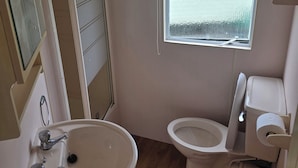 A bathroom with a toilet, sink, and window.