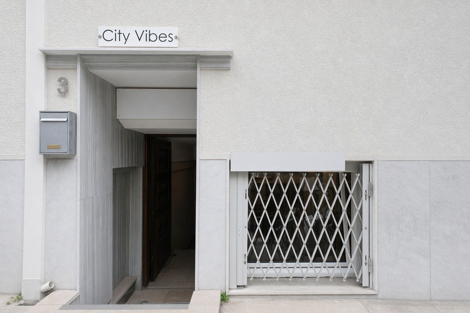 Entrada de un edificio con un letrero que dice 'City Vibes' y un buzón.
