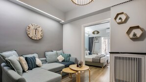A modern living room with a grey sofa, a round wooden table, and a wall clock. - City Vibes - 2-BR Apt. with Backyard in kolonaki (Athens)