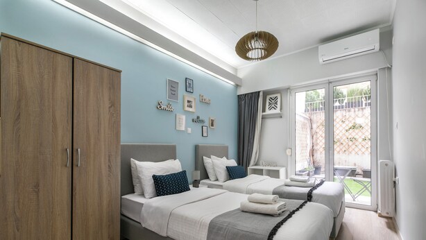 A bedroom with two beds, a wardrobe, a ceiling fan, and a sliding glass door to the outside. - City Vibes - 2-BR Apt. with Backyard in kolonaki (Athens)