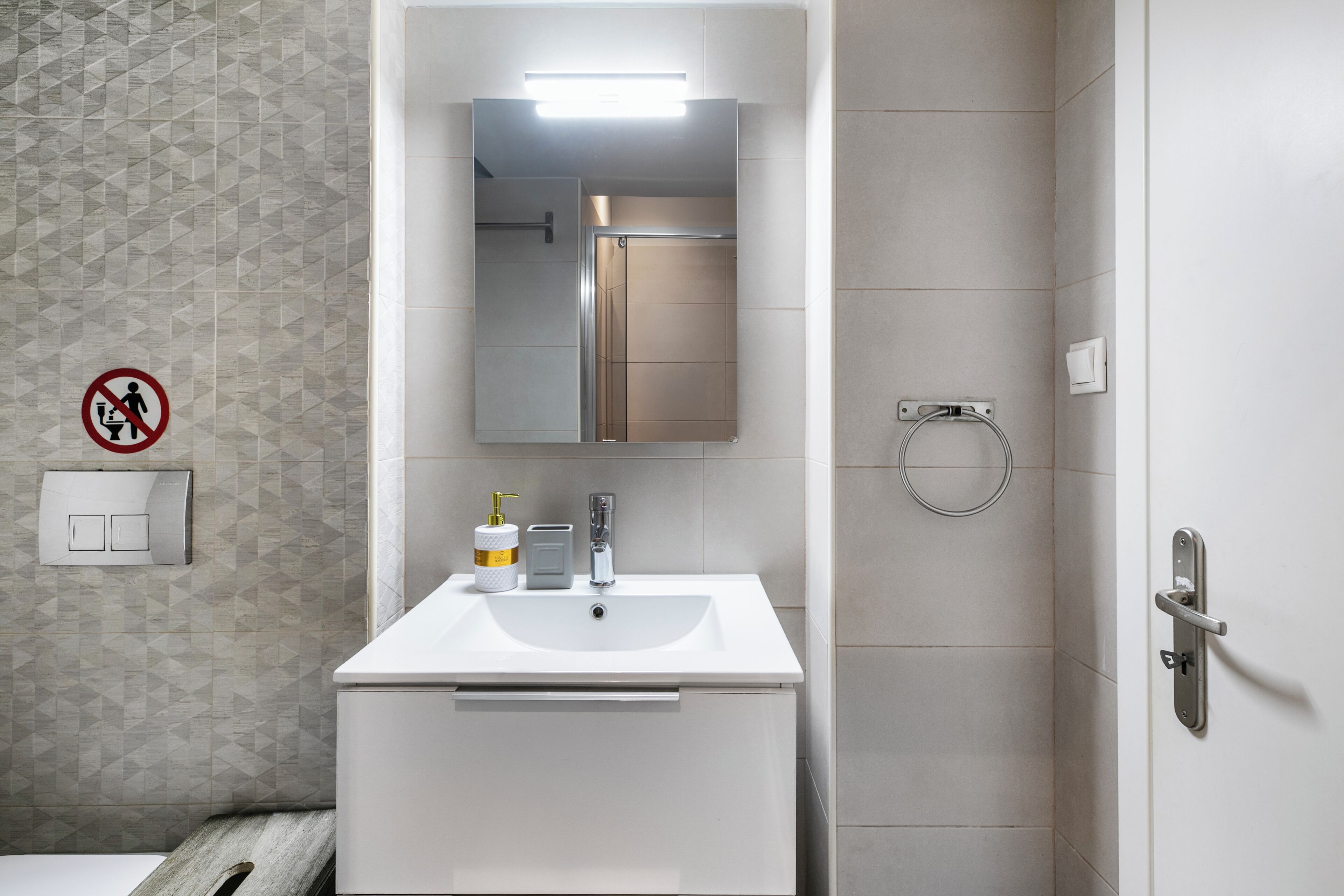 Ein Badezimmer mit weißem Waschbecken, Spiegel und Handtuchhalter.