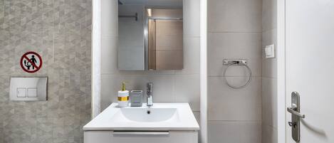 Ein Badezimmer mit weißem Waschbecken, Spiegel und Handtuchhalter.