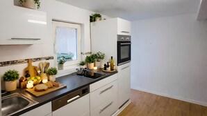 Eine moderne Küche mit weißen Schränken, einer schwarzen Arbeitsplatte und einem Fenster.