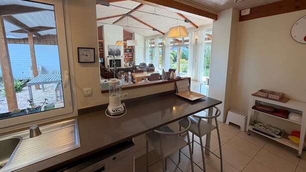 Una cocina con un ventanal grande, una licuadora y una zona de bar con taburetes.