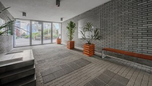 Un hall d’entrée moderne avec un mur en briques, un banc en bois et des plantes en pot.